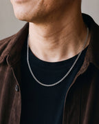 Close-up of the slim 3 mm silver Atlas Cuban chain at the collar worn, true size