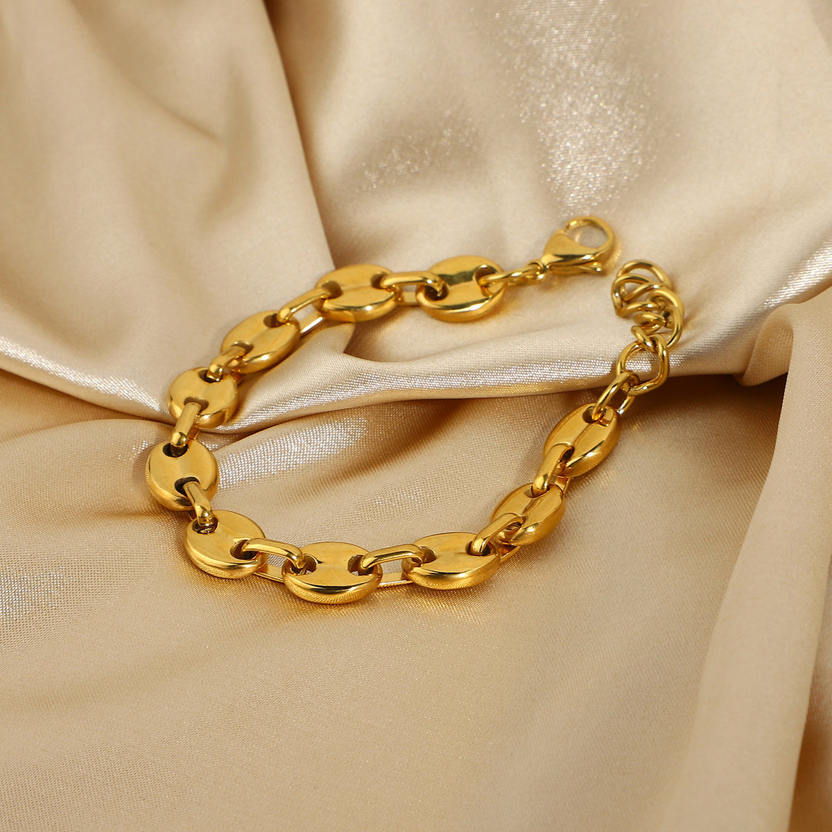 Gold-Tone Coffee Bean Link Bracelet on a light gold fabric background view 3