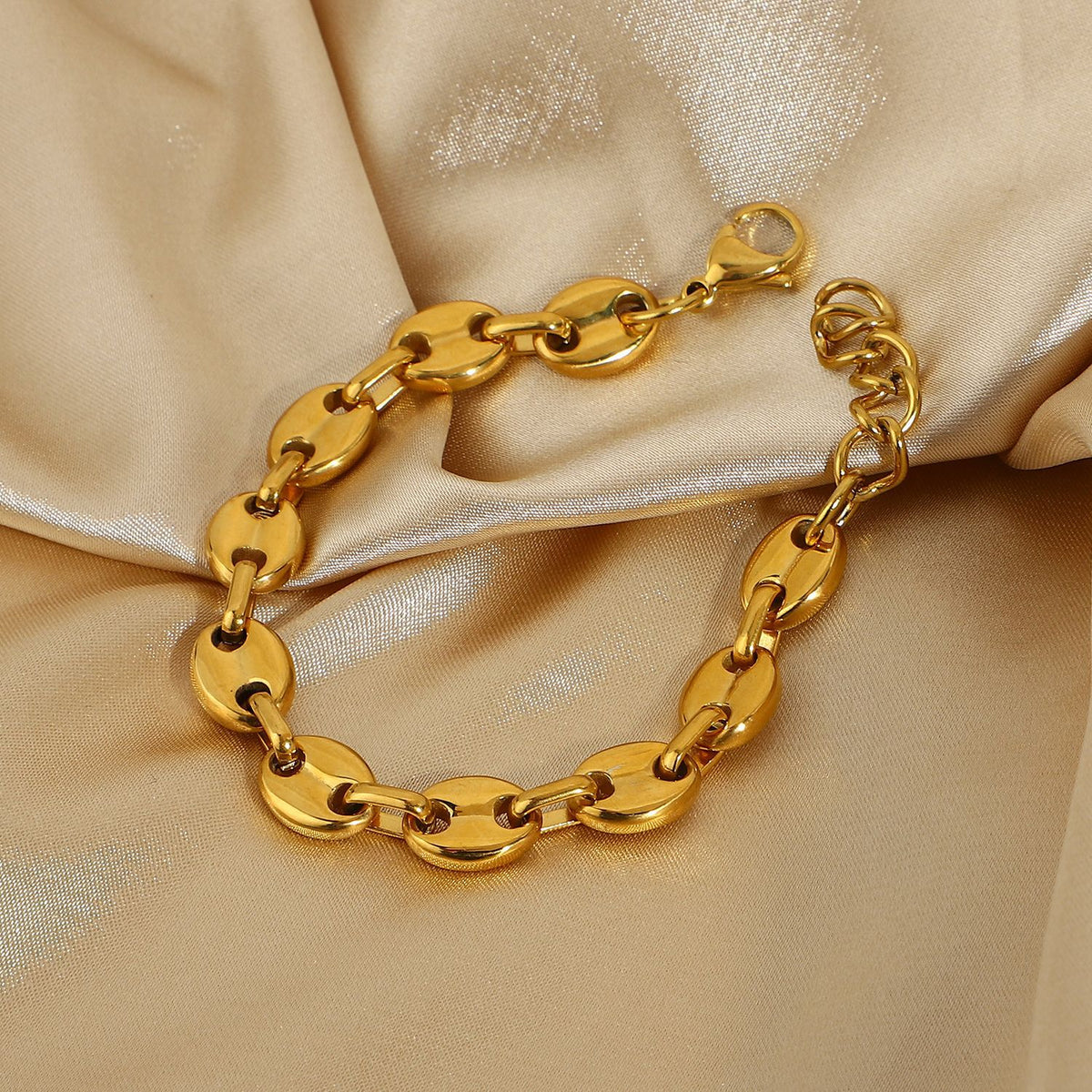 Gold-Tone Coffee Bean Link Bracelet on a light gold fabric background view 2