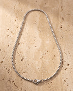 The whole silver-tone Atlas 1.5 mm box chain laid on warm stone