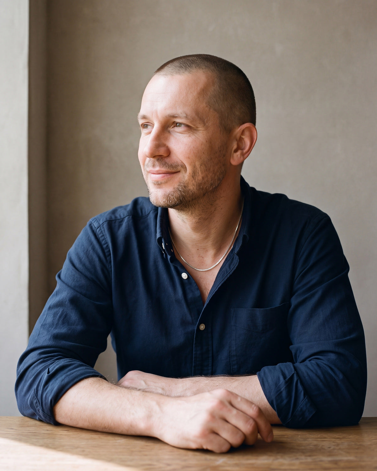 Man in a dark navy cotton oxford shirt by a window wearing the silver Atlas 1.5mm Box Chain