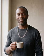 Smiling man in a charcoal knit holding a coffee cup wearing the silver Atlas 10 mm Cuban link chain