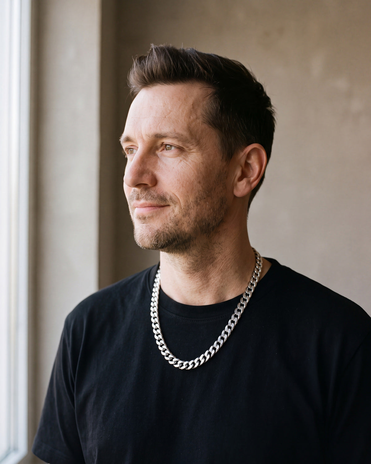 Man in a black T-shirt by a window wearing the silver Atlas 10 mm Cuban link chain