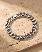 The whole silver-tone Atlas 10 mm Cuban link bracelet closed on warm stone