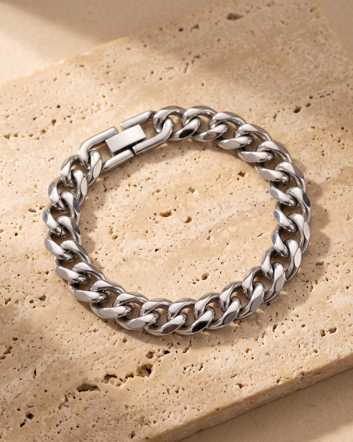The whole silver-tone Atlas 10 mm Cuban link bracelet closed on warm stone