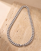 The whole silver-tone Atlas 10 mm Cuban link chain laid on warm stone