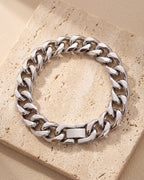 The whole silver Atlas 11mm Cuban Link Bracelet lying on warm travertine stone