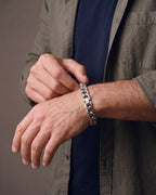 Hand adjusting the Atlas 11mm Silver Cuban Link Bracelet on the wrist