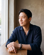 Man in a dark navy linen shirt by a window wearing the silver-tone Atlas 14mm Braided Leather Bracelet with Magnetic Clasp