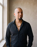 Man in a black shirt by a window wearing the Atlas 14 mm Cuban chain in gold-tone steel