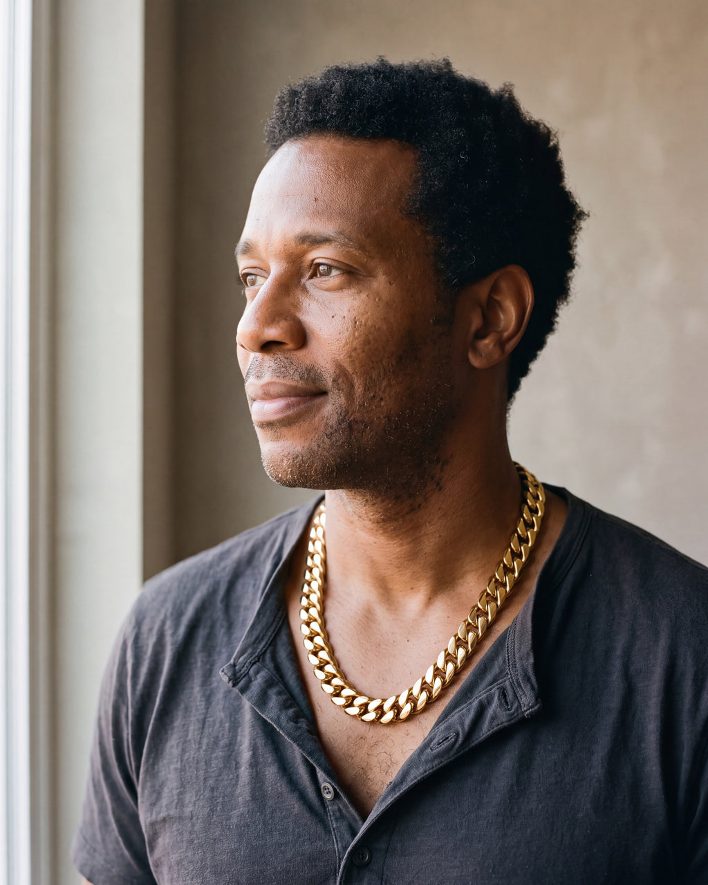 Man in a charcoal henley wearing the Atlas 14 mm Cuban chain in gold-tone steel