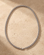 The whole silver-tone Atlas wheat chain lying on warm travertine stone