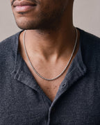 Close-up of the silver Atlas 2mm Rolo Link Chain in Stainless Steel worn by a man, shown at true size