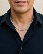 Close-up of the silver Atlas 3 mm wheat chain worn by a man, shown at true size