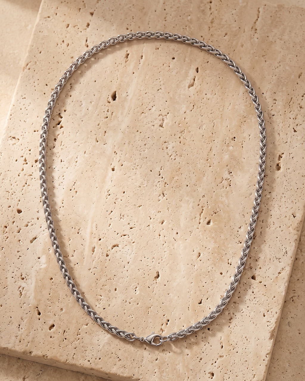 The whole silver-tone Atlas 3 mm wheat chain laid on warm stone