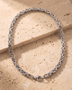 Silver-tone Atlas Byzantine chain laid whole on warm stone