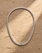 The silver Atlas 4mm Tennis Chain laid on warm travertine stone