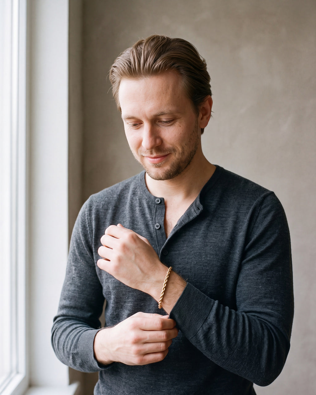 Man in a charcoal knit henley wearing the Atlas 5 mm rope chain bracelet in gold-tone steel