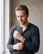 Man in a charcoal knit henley wearing the Atlas 5 mm rope chain bracelet in gold-tone steel