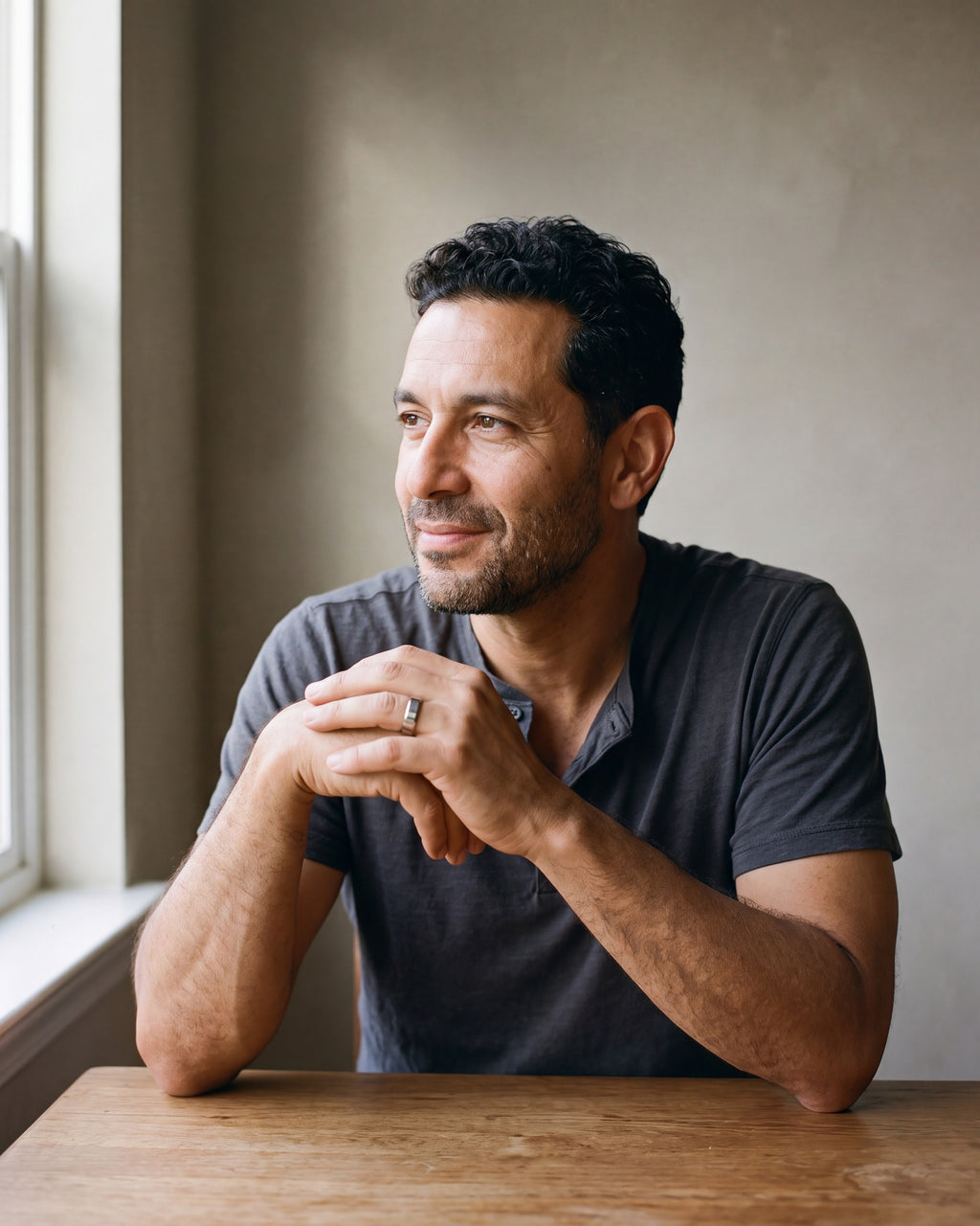 Man in a charcoal henley seated at a wooden table wearing the silver-tone Atlas 6 mm beveled band
