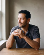 Man in a charcoal henley seated at a wooden table wearing the silver-tone Atlas 6 mm beveled band