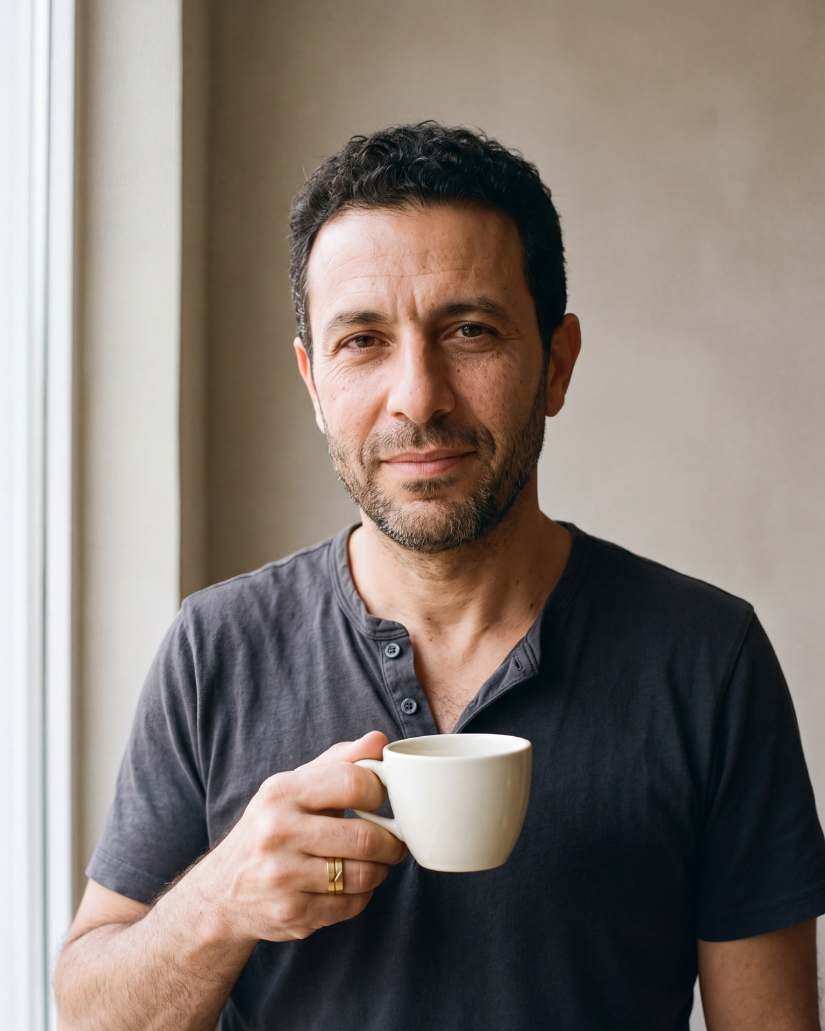 Man in a charcoal henley holding a coffee cup wearing the gold-tone Atlas 6 mm geometric cut-out ring