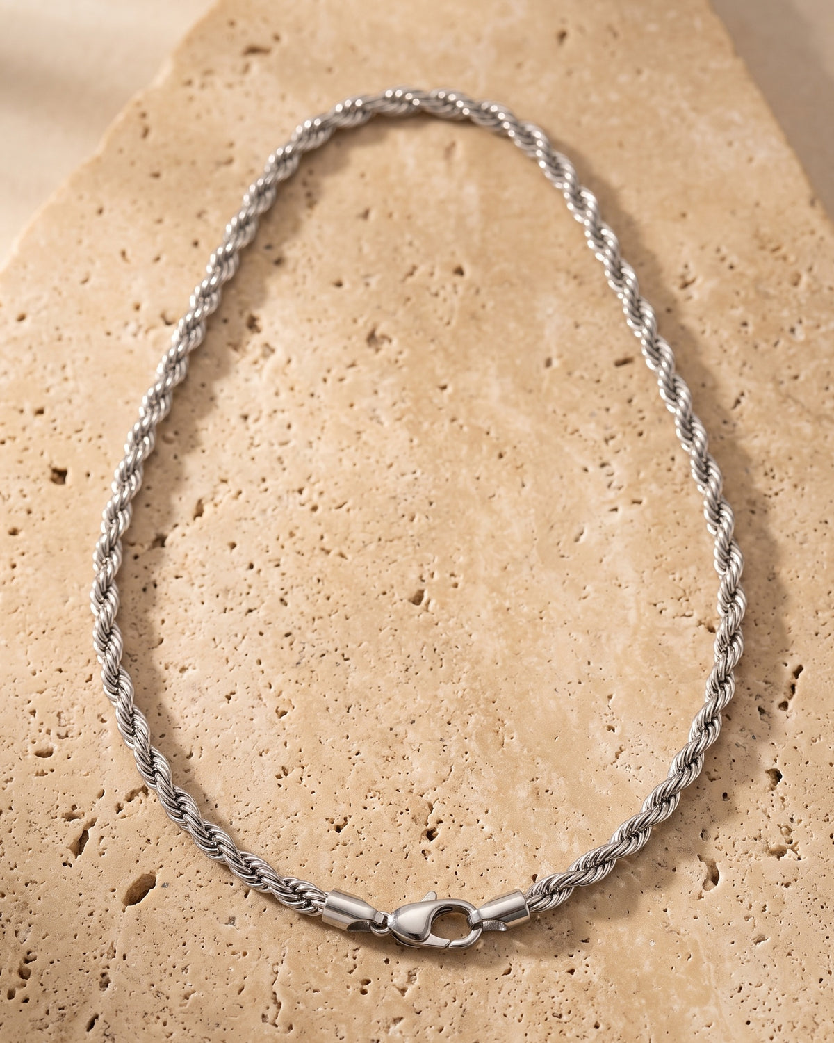 The whole silver Atlas 6 mm rope chain laid on warm stone, lobster clasp closed