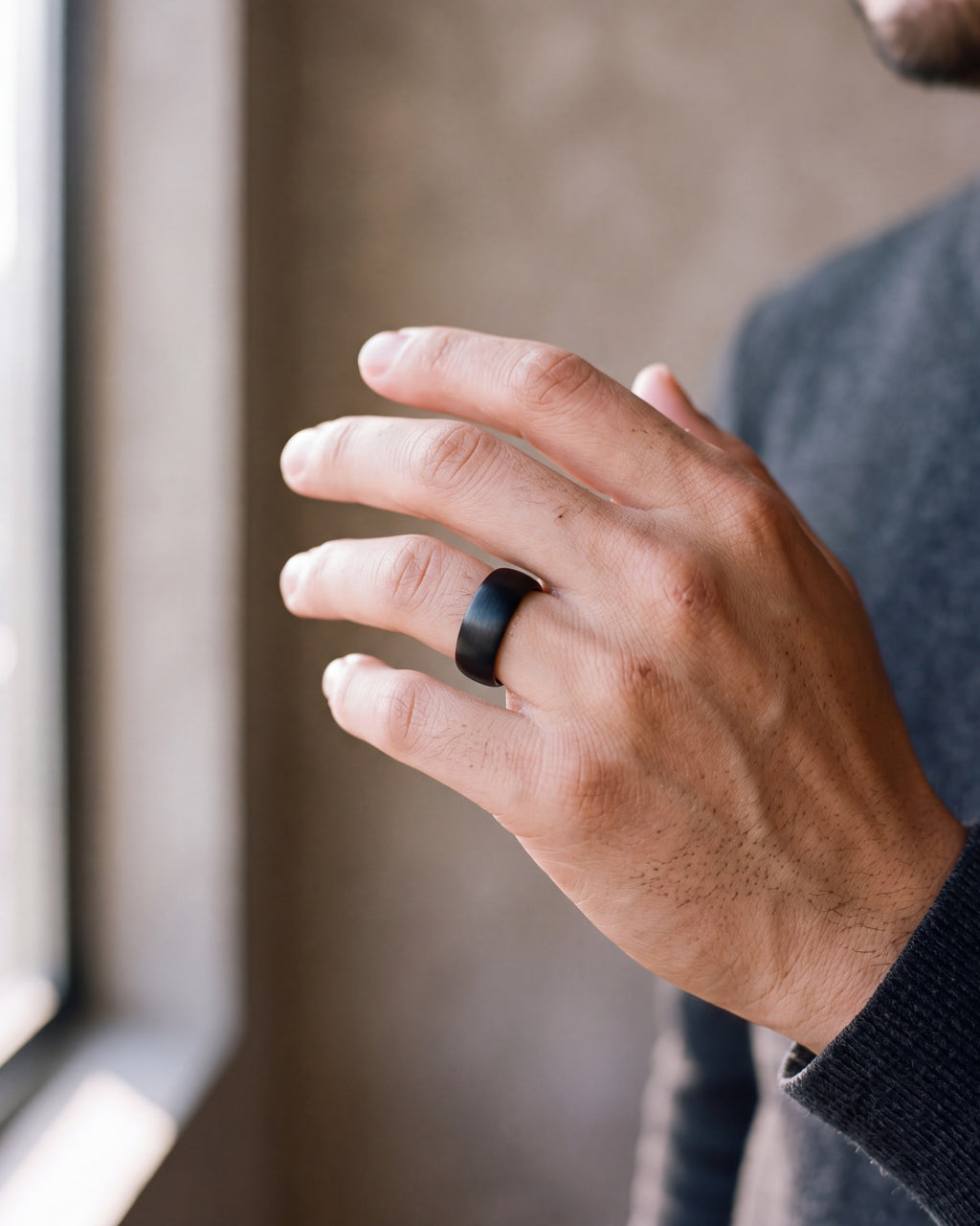 Close-up of the black Atlas 8 mm brushed black tungsten carbide ring worn by a man, shown at true size