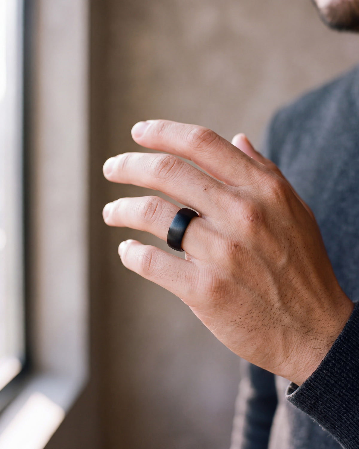 Close-up of the black Atlas 8 mm brushed black tungsten carbide ring worn by a man, shown at true size