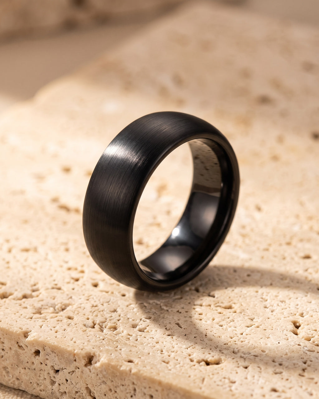 The whole black Atlas 8 mm brushed black tungsten carbide ring laid on warm stone