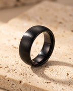 The whole black Atlas 8 mm brushed black tungsten carbide ring laid on warm stone