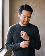 Man in a charcoal sweater adjusting his sleeve wearing the black Atlas 8 mm brushed black tungsten carbide ring