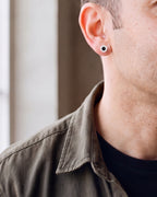 Close-up of the silver-tone Atlas 8mm Roman numeral stud earring on the earlobe at true size