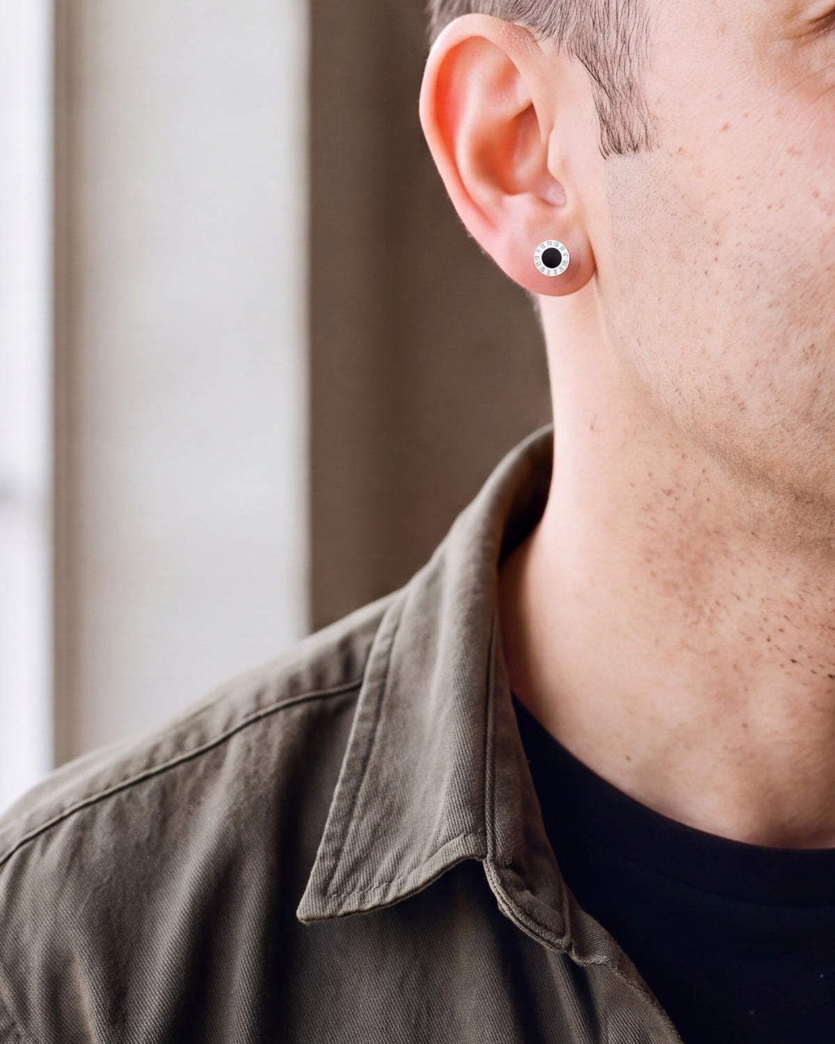 Close-up of the silver-tone Atlas 8mm Roman numeral stud earring on the earlobe at true size