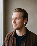 Man in a brown shirt wearing the gold-tone Atlas 8mm Roman numeral stud earring with cubic zirconia, at true size