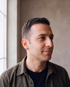 Man in an olive overshirt wearing the silver-tone Atlas 8mm Roman numeral stud earring, shown at true size