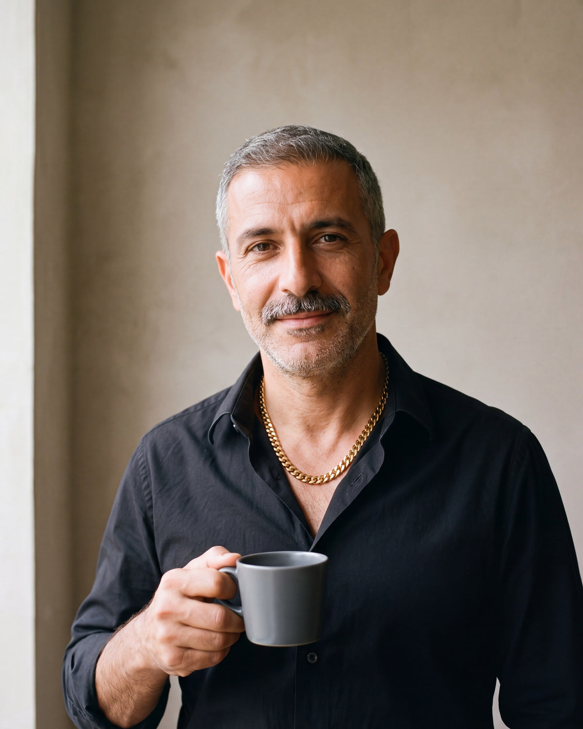 Man in a black shirt holding a coffee cup, wearing the 9 mm gold-tone Atlas Cuban chain