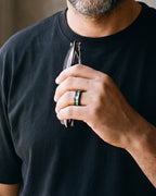 Close-up of a man's hand wearing the Atlas abalone inlay black band at true size