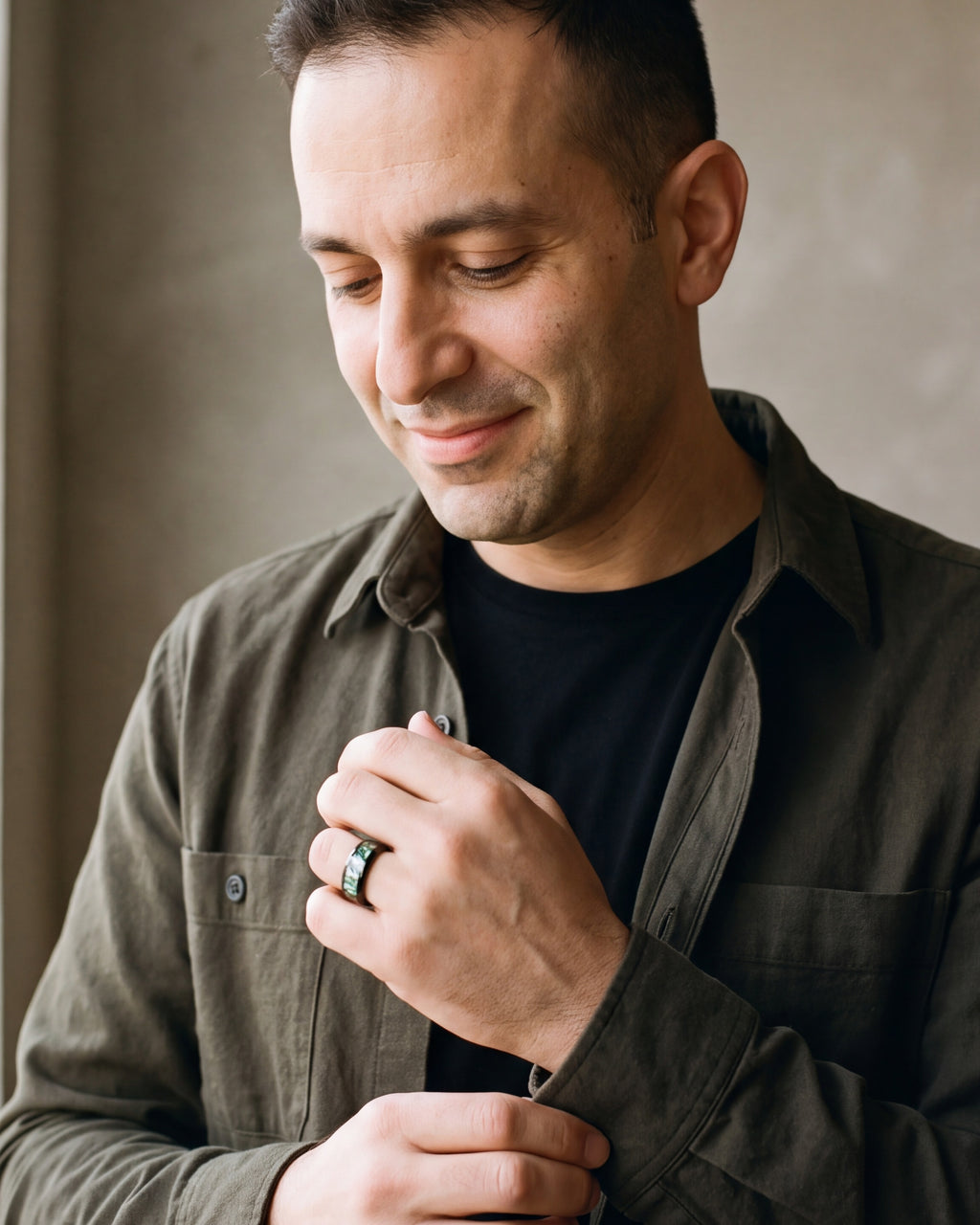 Man in an olive overshirt adjusting his sleeve, wearing the Atlas abalone inlay black band