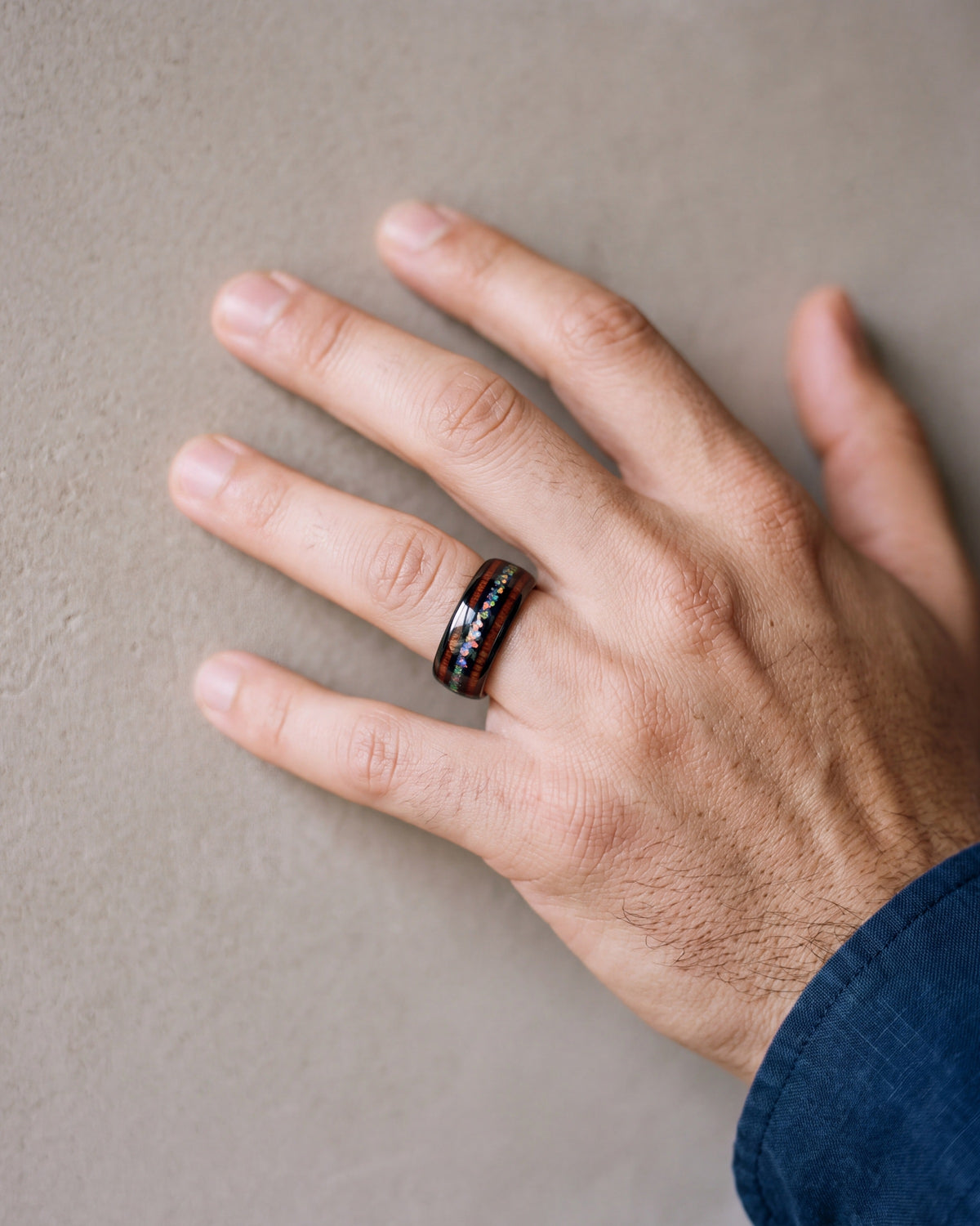 Close-up of the Atlas wood and opal black tungsten band on a man's hand
