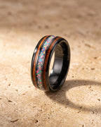 The Atlas acacia wood and opal black tungsten band standing on warm stone