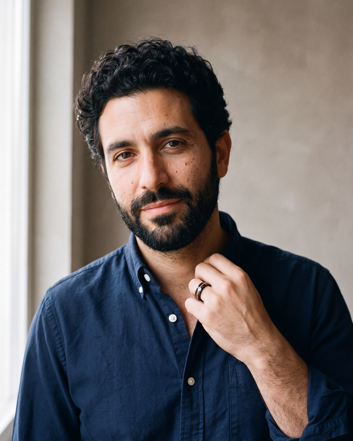 Man in a navy shirt wearing the Atlas acacia wood and opal black tungsten band