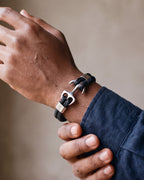 Close-up of the silver Atlas anchor bracelet on a man's wrist at true size, two braided leather strands