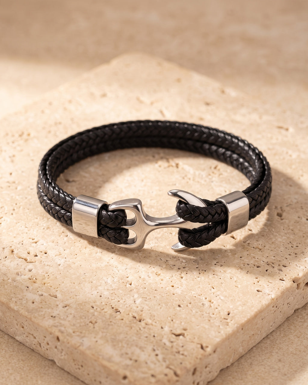 Silver Atlas braided leather anchor bracelet closed on warm travertine stone