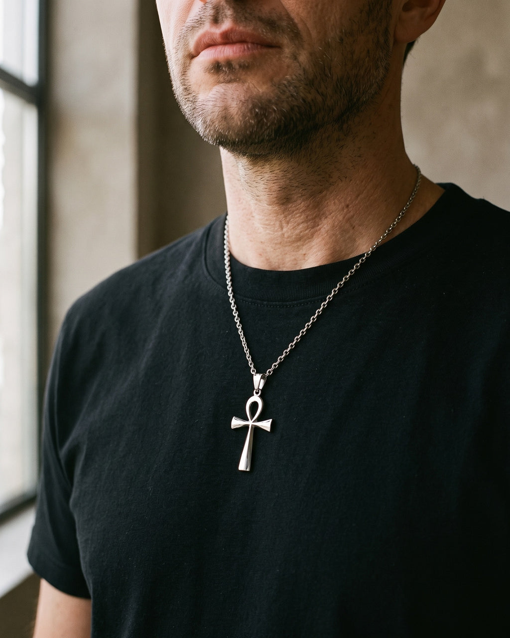 Atlas ankh cross pendant necklace in silver-tone titanium steel worn on the chest, close-up