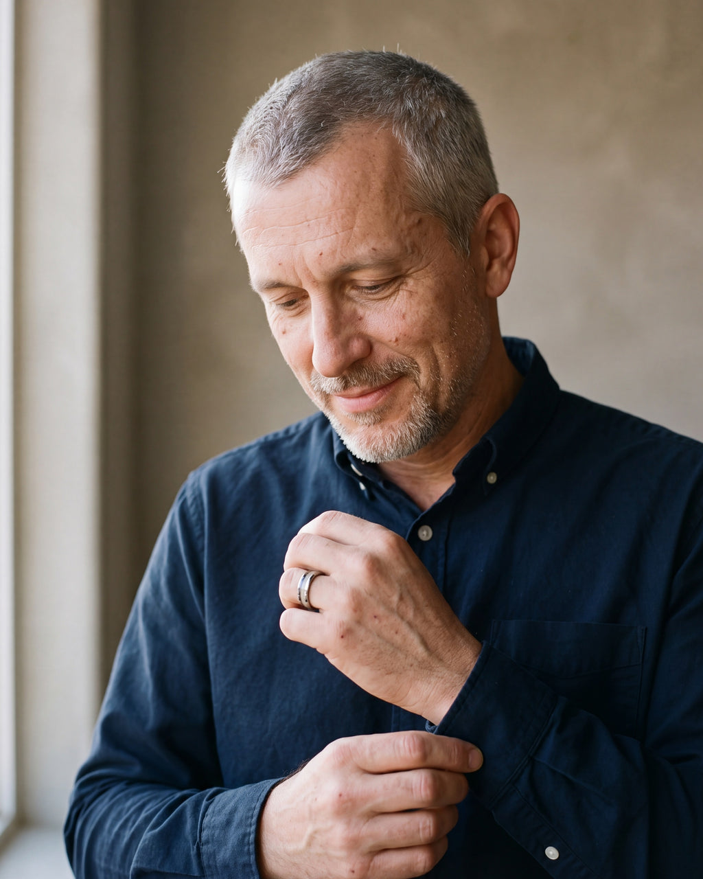 Man in a navy shirt adjusting his cuff, wearing the Atlas antler inlay tungsten ring