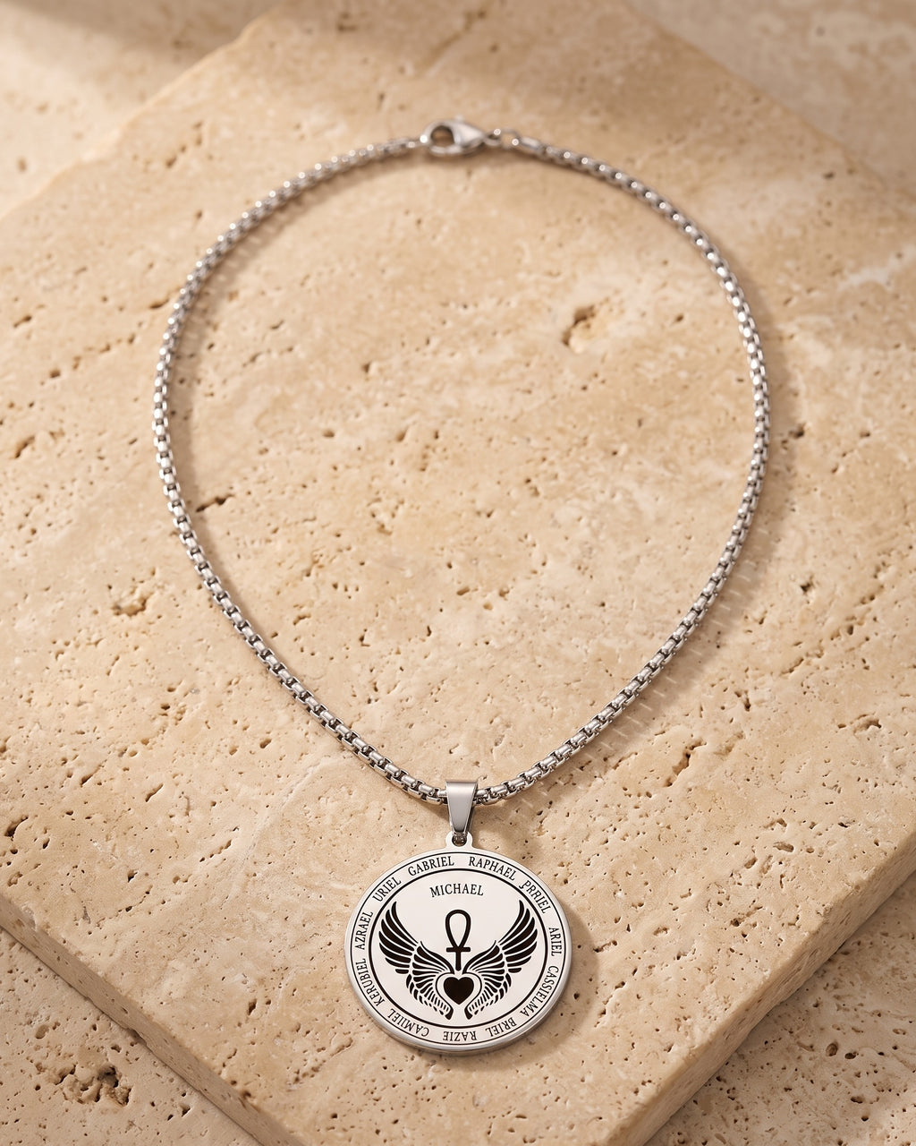 The whole silver-tone Atlas Archangel Michael ankh pendant necklace laid on warm stone