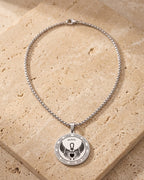 The whole silver-tone Atlas Archangel Michael ankh pendant necklace laid on warm stone