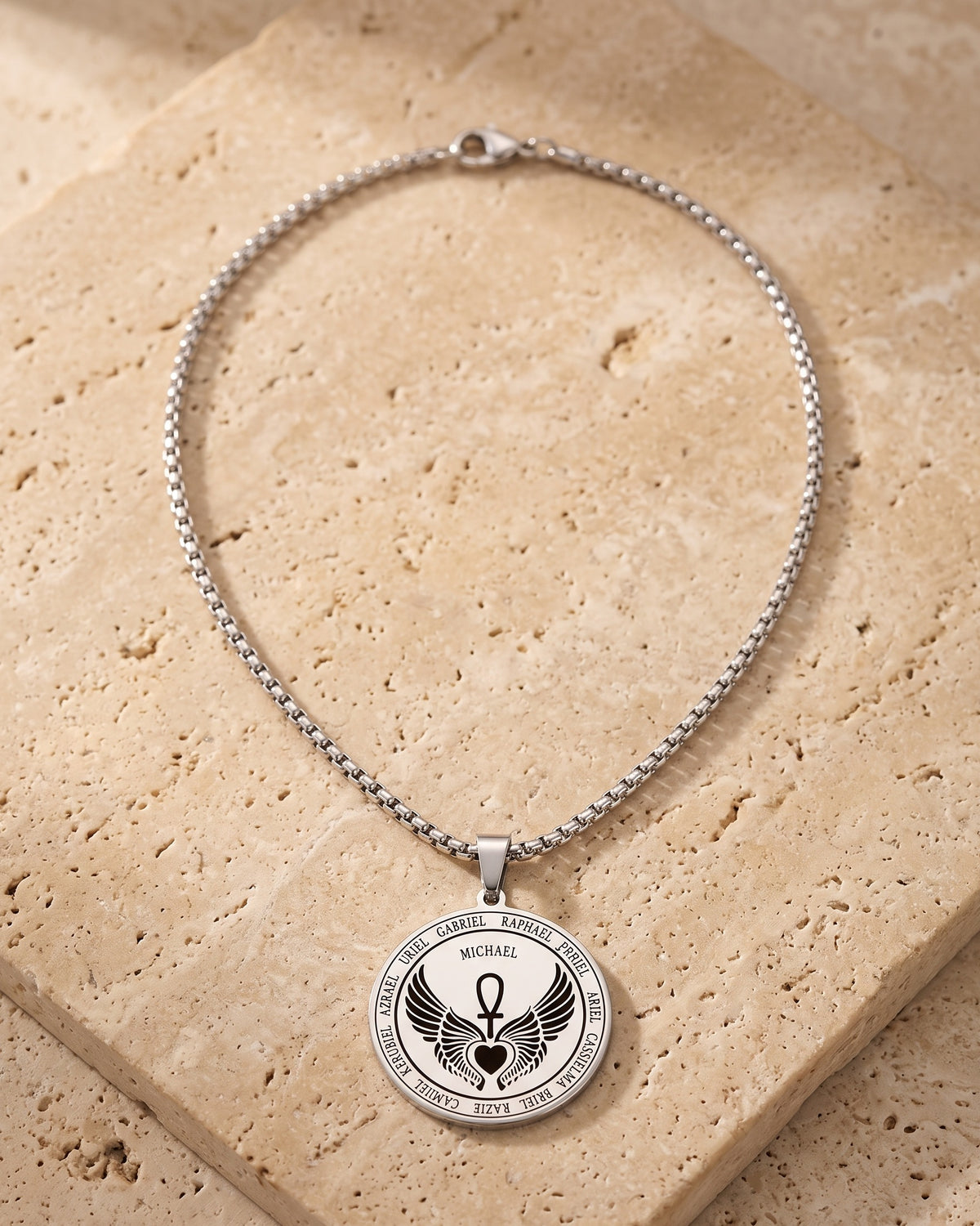 The whole silver-tone Atlas Archangel Michael ankh pendant necklace laid on warm stone