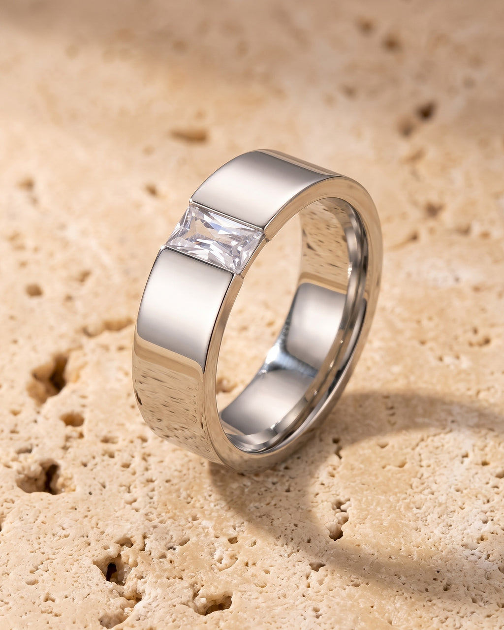 The whole silver-tone Atlas Baguette Cubic Zirconia Ring lying on warm travertine stone